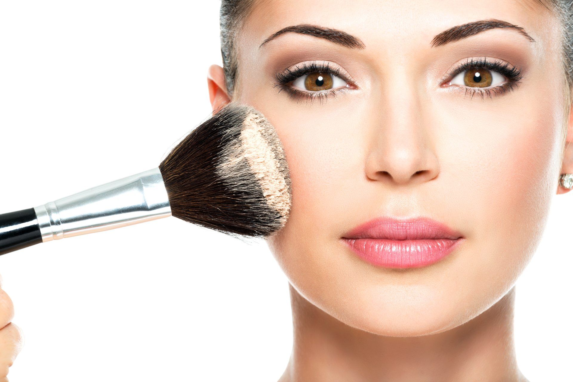 A woman applies foundation with a brush - Maybelline makeup