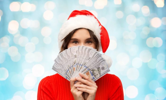 woman in Santa hat holding money from class action rebates