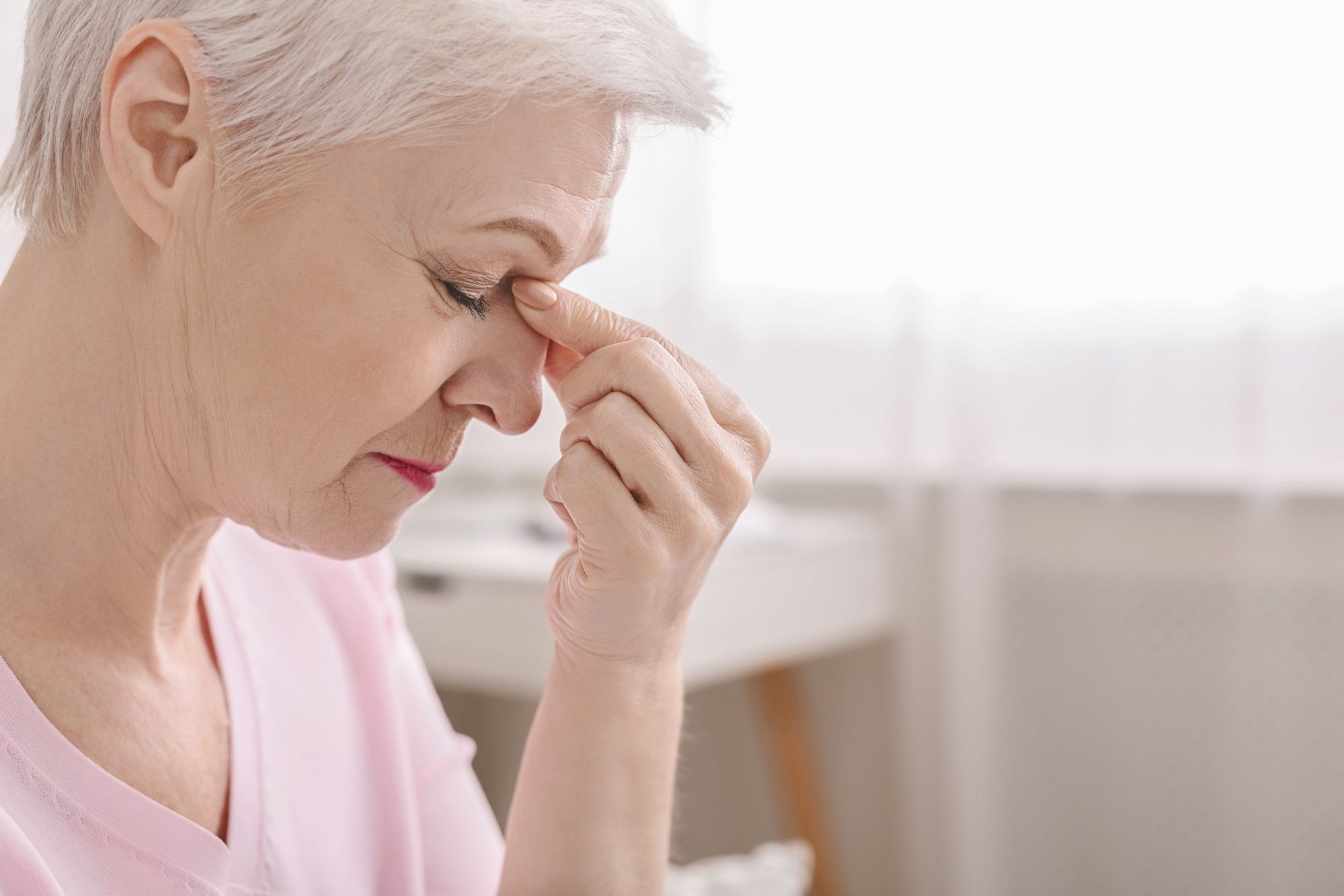 Elderly woman suffering headache from vision difficulty, leading to potential Elmiron lawsuits.