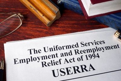 A paper lying on a desk with books and glasses reads "The Uniformed Services Employment and Reemployment Rights Act of 1994 USERRA" - military leave