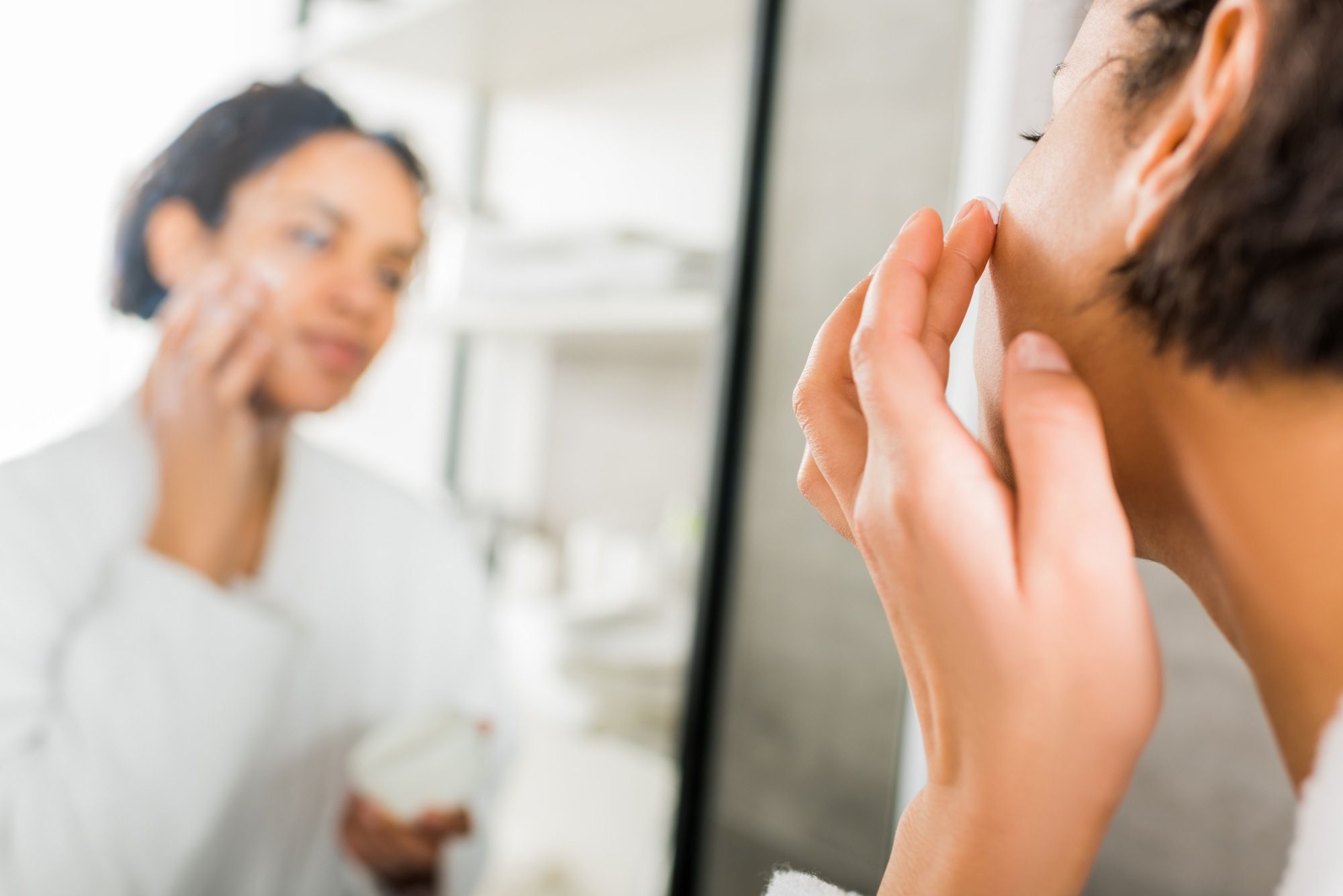 black-woman-mirror-reflection-applying-moisturizer