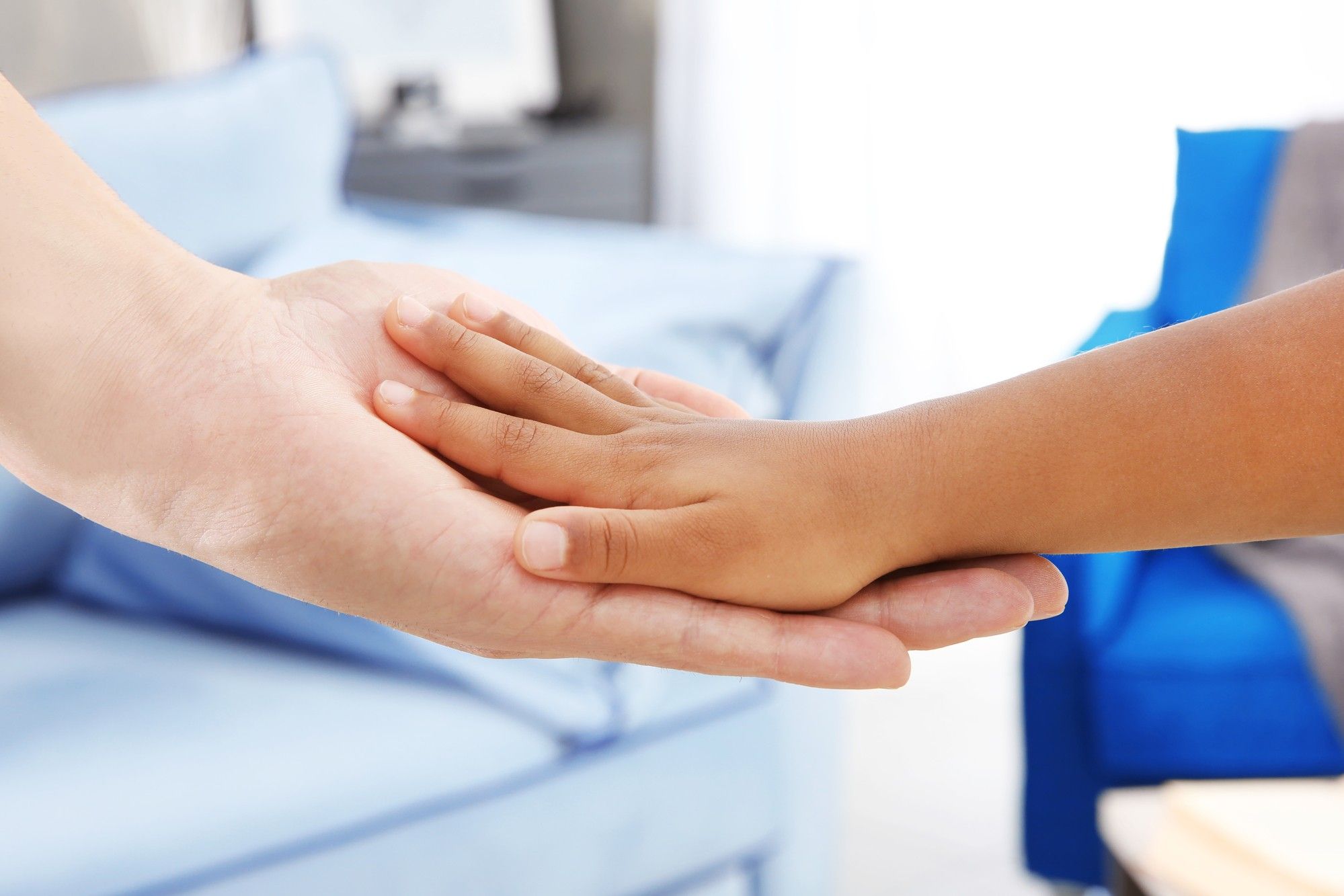 Hands of a parent and child in a foster care home.