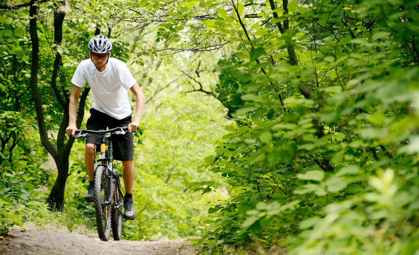A man rides a bike in the woods while wearing a helmet - Trek Bicycle helmet