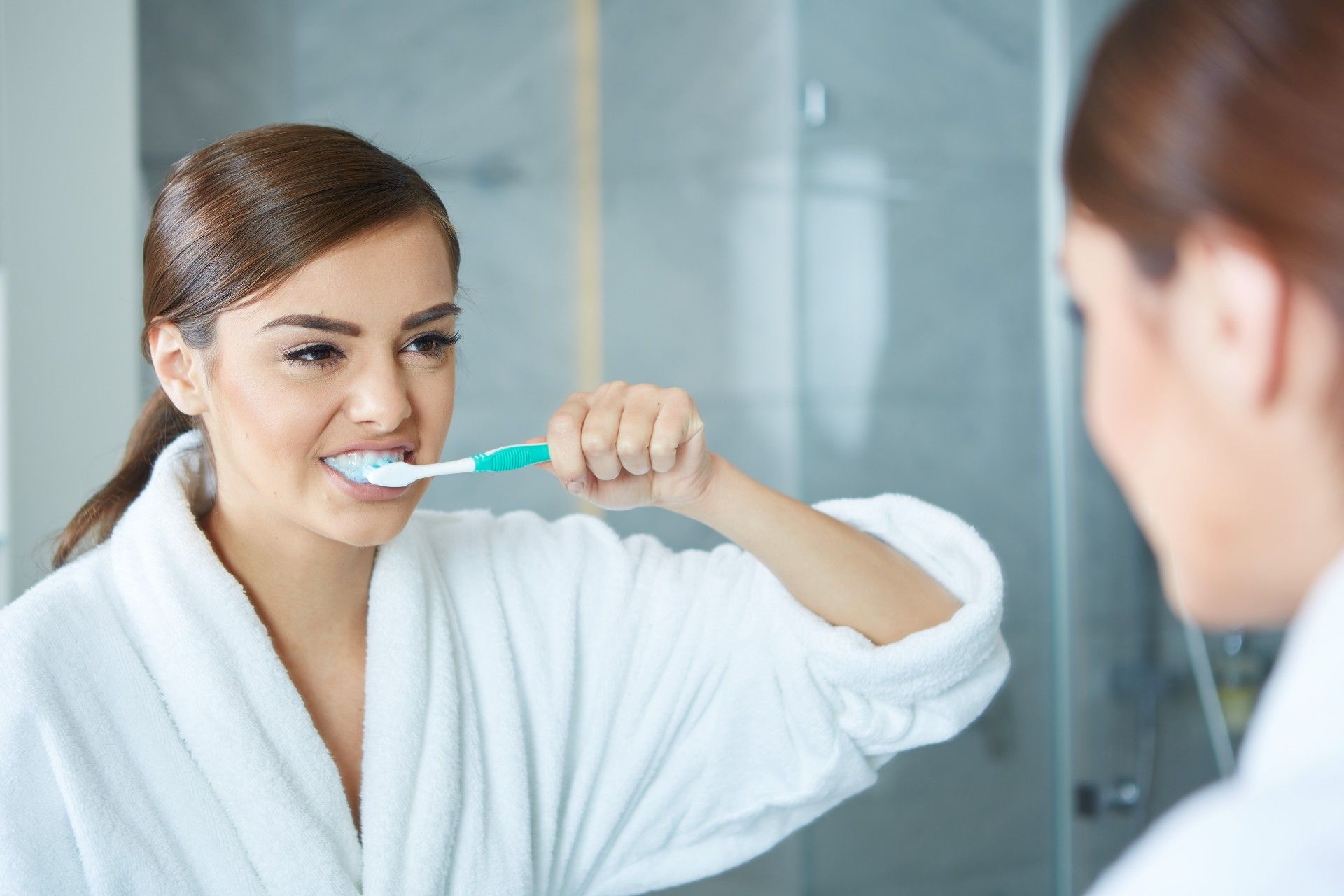 A woman brushes her face in front of a bathroom mirror - Crest toothpaste