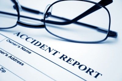 A pair of glasses lies on top of an accident report form - crash reports