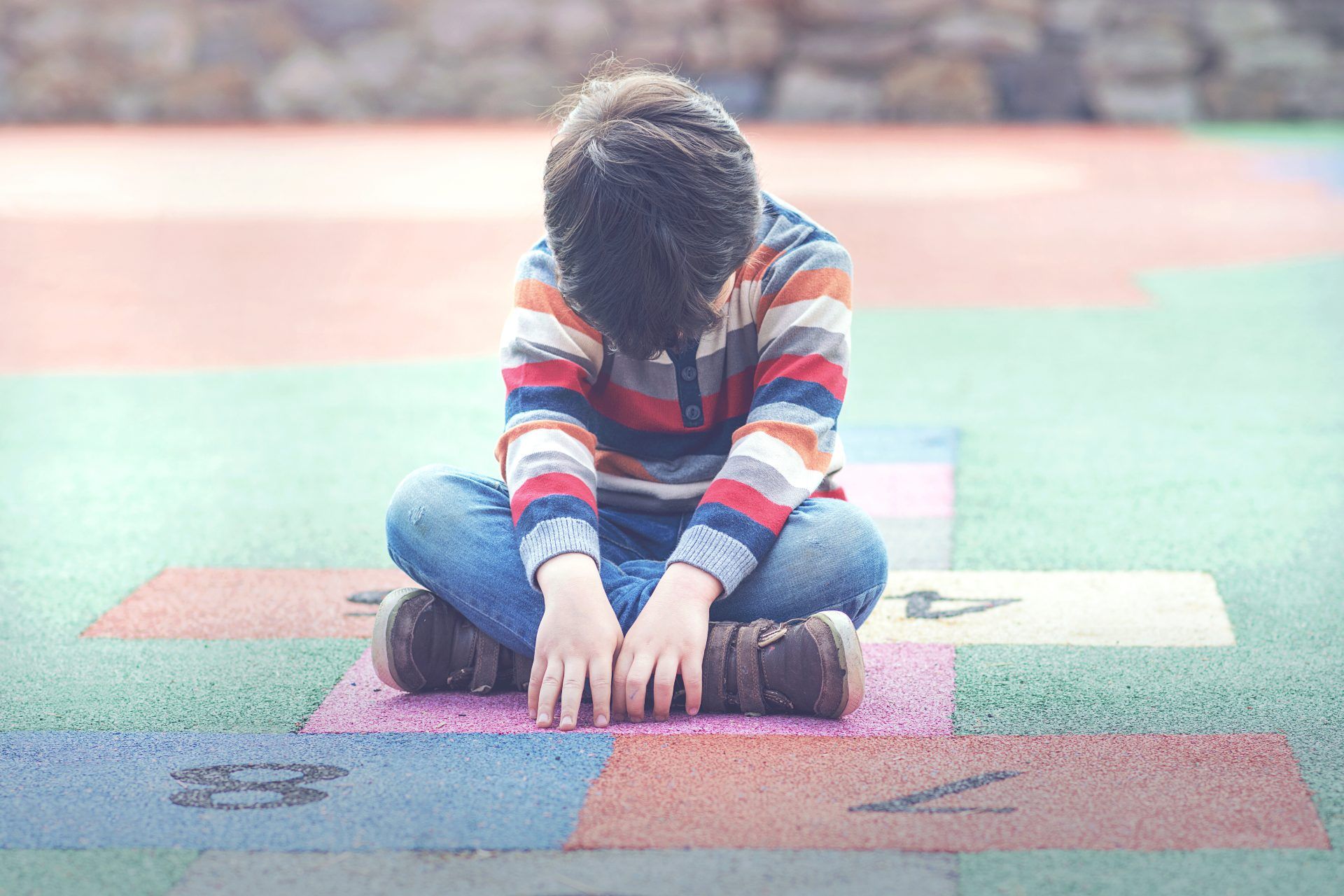 A boy sits cross-legged on a hopscotch board - sexual assault