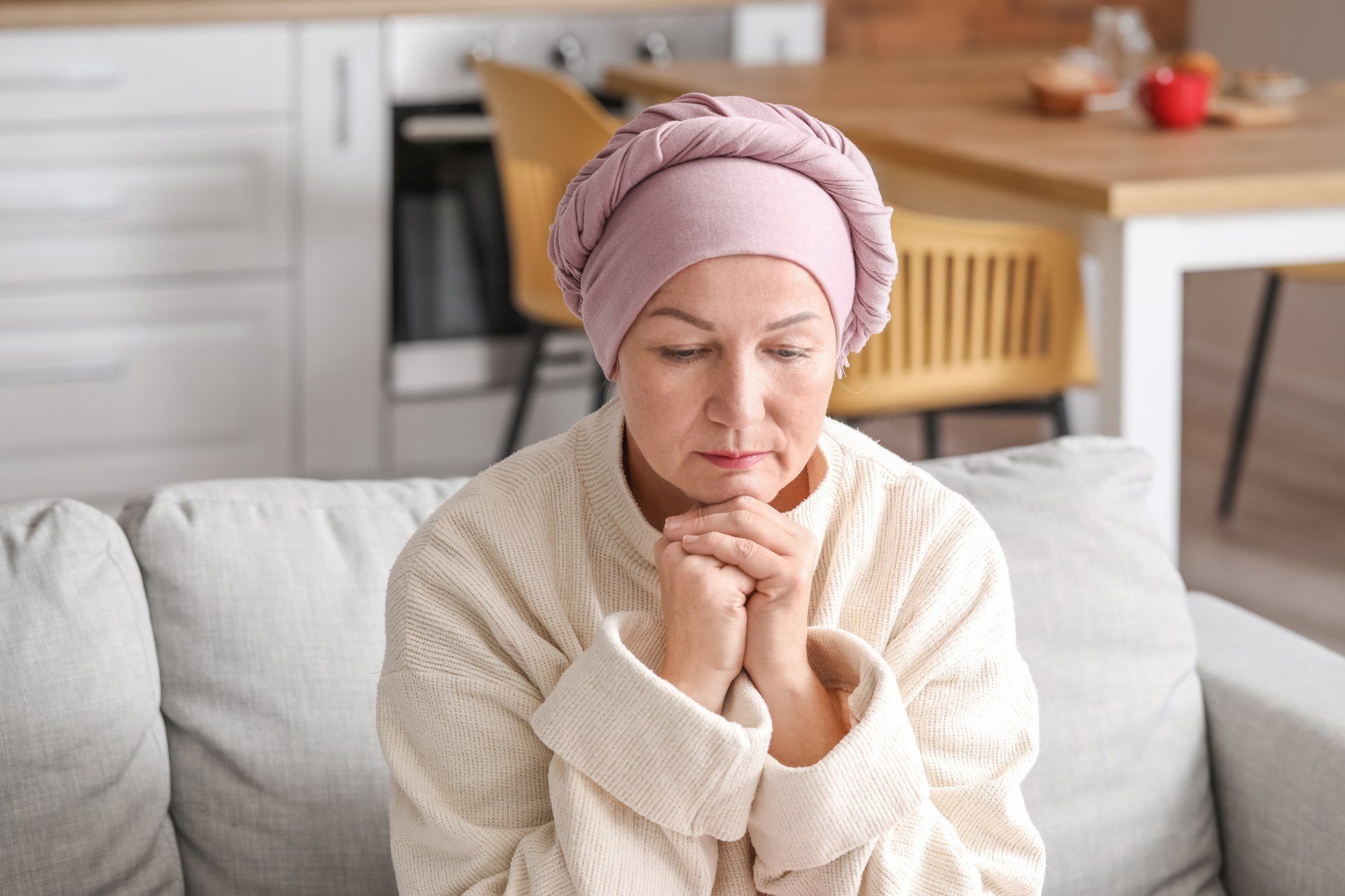A woman with a head covering sits at home after chemotherapy - texas electric grid