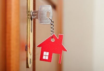 A key with a hanging house keychain is in the lock on a door - nationstar mortgage settlement