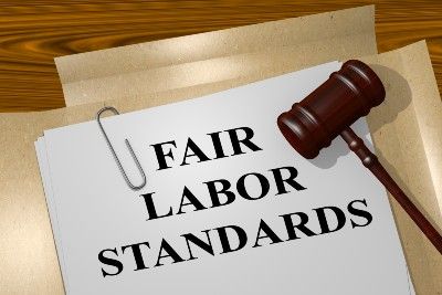 A paper lying in a folder reads "fair labor standards" with a gavel lying on top - google