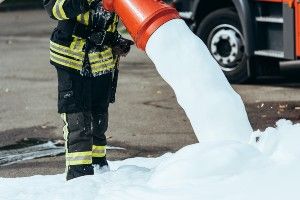 A firefighter pours firefighting foam on the ground