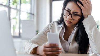 Frustrated woman sits with head in one hand while holding smartphone with the other - data throttling