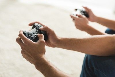 Close up of two people's hands holding video game controllers - epic games