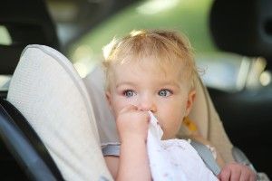 A toddler sits in a car seat, looking out the window - booster seat