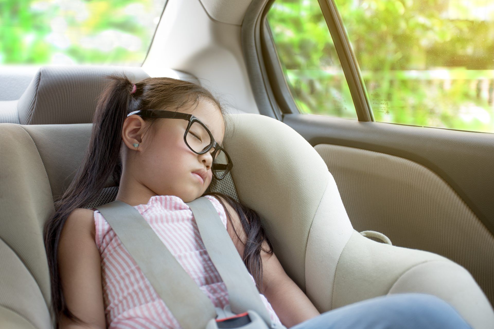 Young girl in glasses sleeps in a car seat - booster seat
