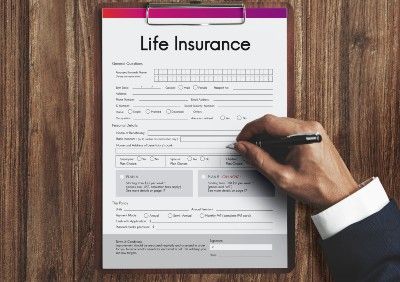Closeup of a man's hand holding a pen to a life insurance form on a clipboard - american general life insurance