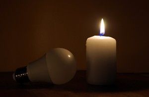 A lightbulb lies next to a lit candle - Texas Electric Grid