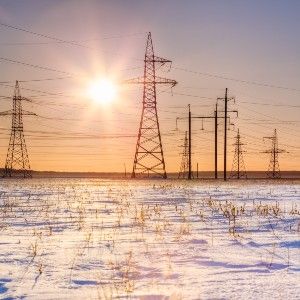 Snow on the ground near power lines, with the sun low in the sky - Texas electric grid failure
