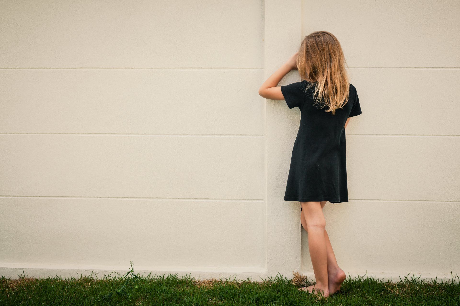 Young girl stands outdoors facing a wall - ymca