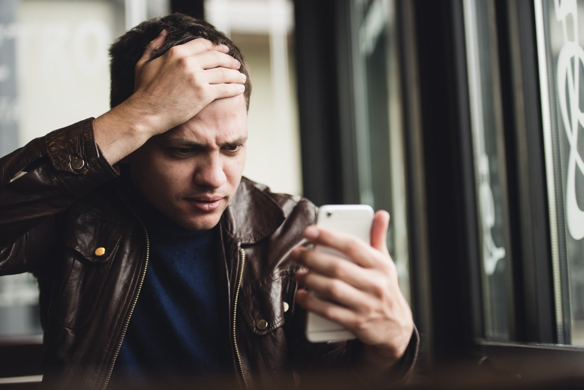 young man looking at phone with shock or annoyance