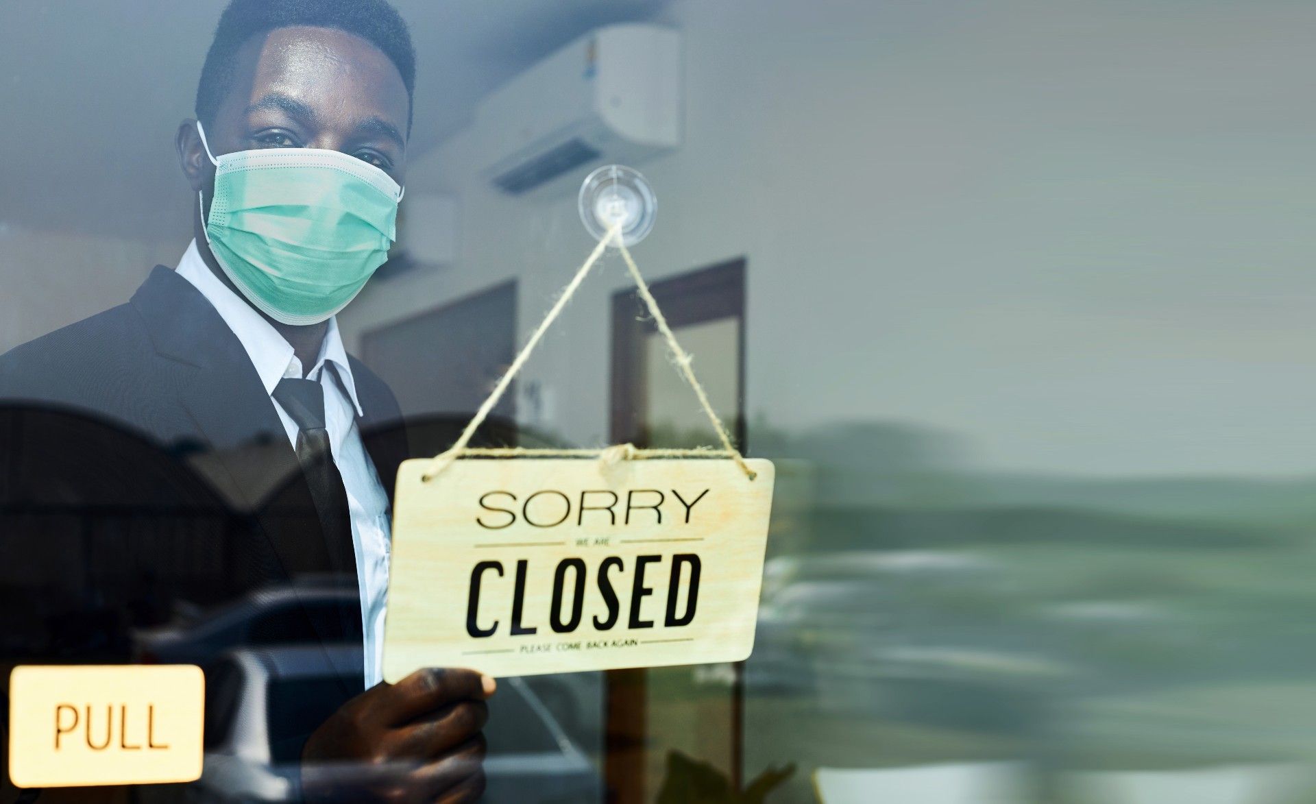 A Black businessman in a green face mask turns the sign on his business to read "Sorry We Are Closed Please Come Back Again" - Oregon Cares