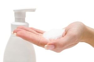 Foaming hand soap in a woman's hand near the dispenser - scent theory