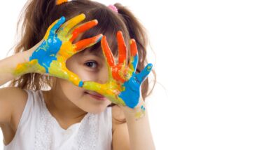 young girl with hands covered in finger paint