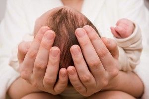 Hands hold a newborn's head - birth injury lawsuit