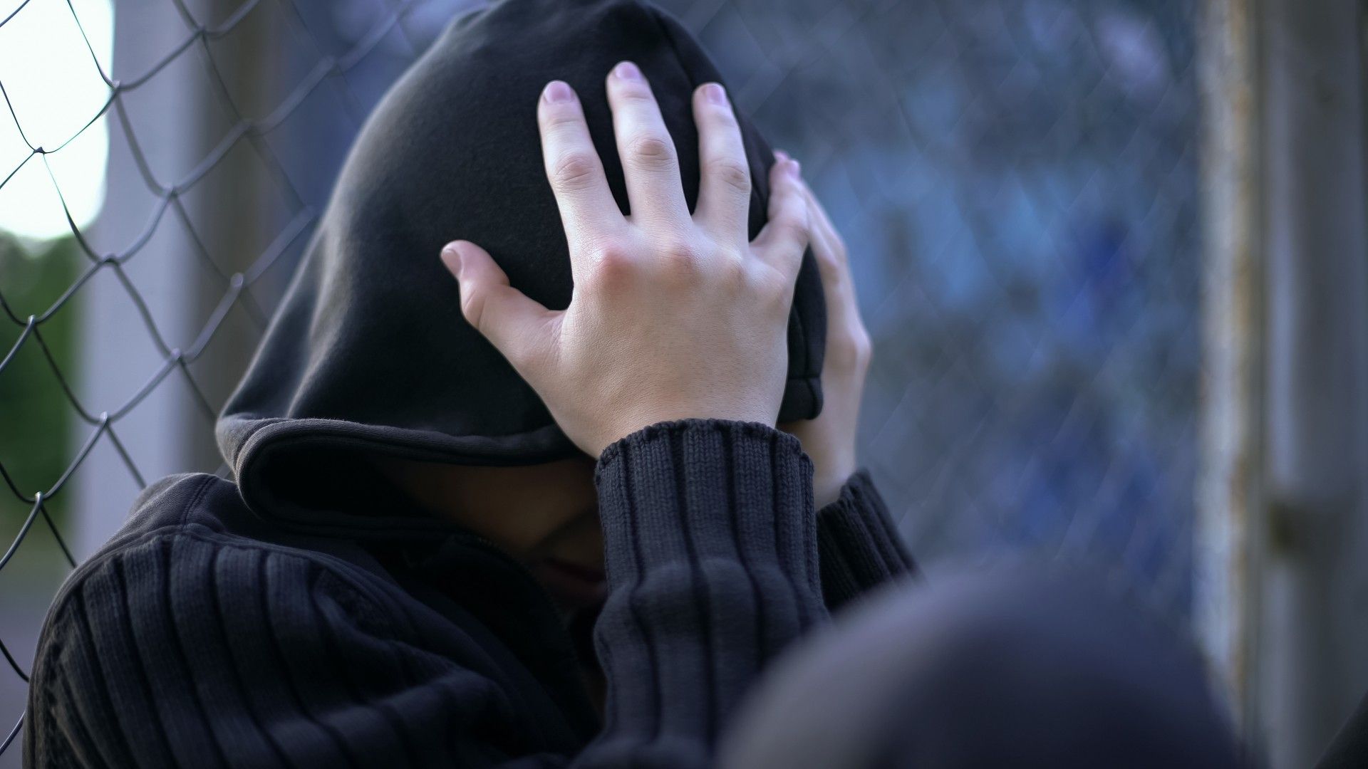 Teen in hoodie holds his head in his hands - boys & girls club