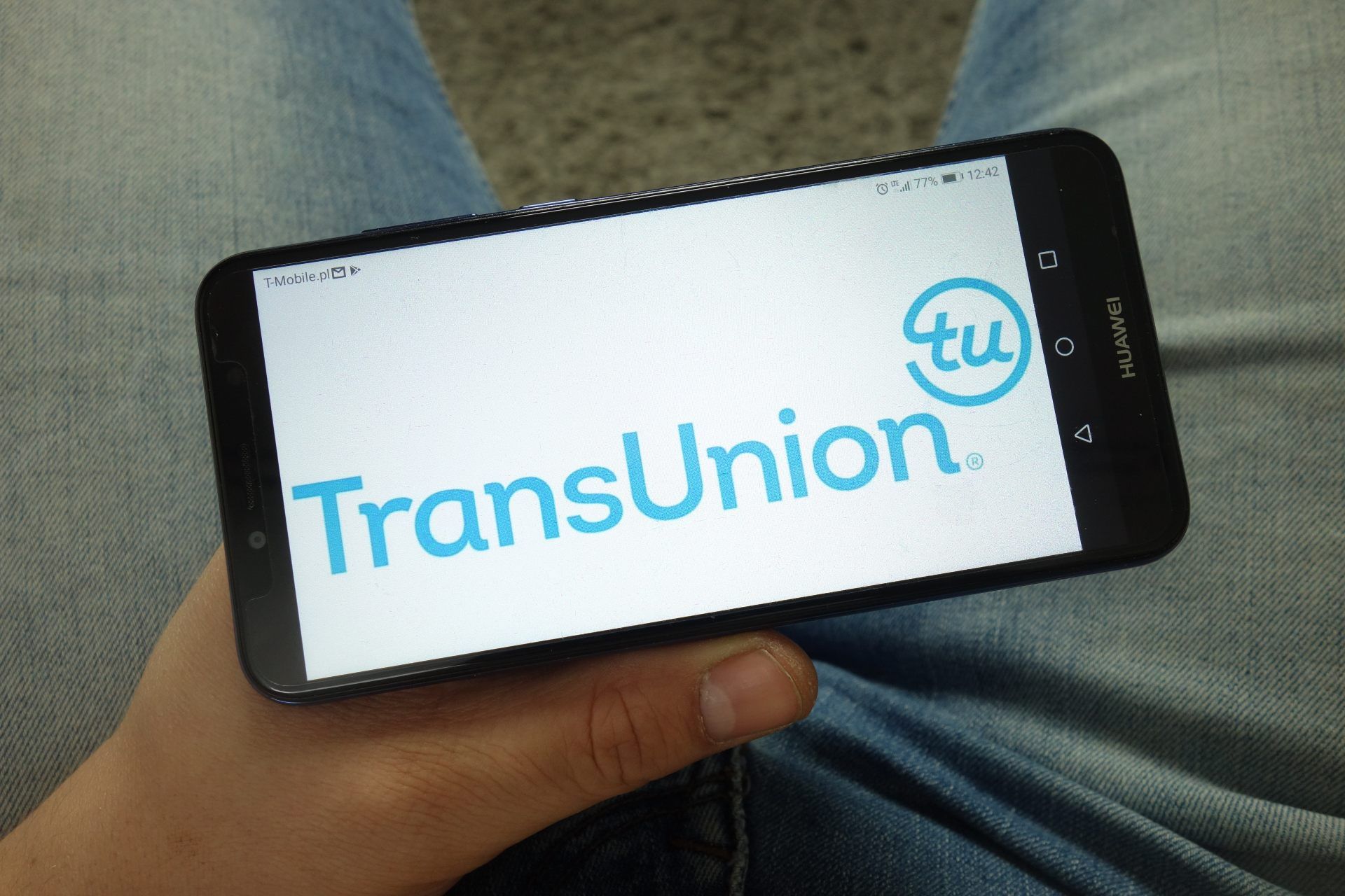 A person holds a smartphone showing the TransUnion logo