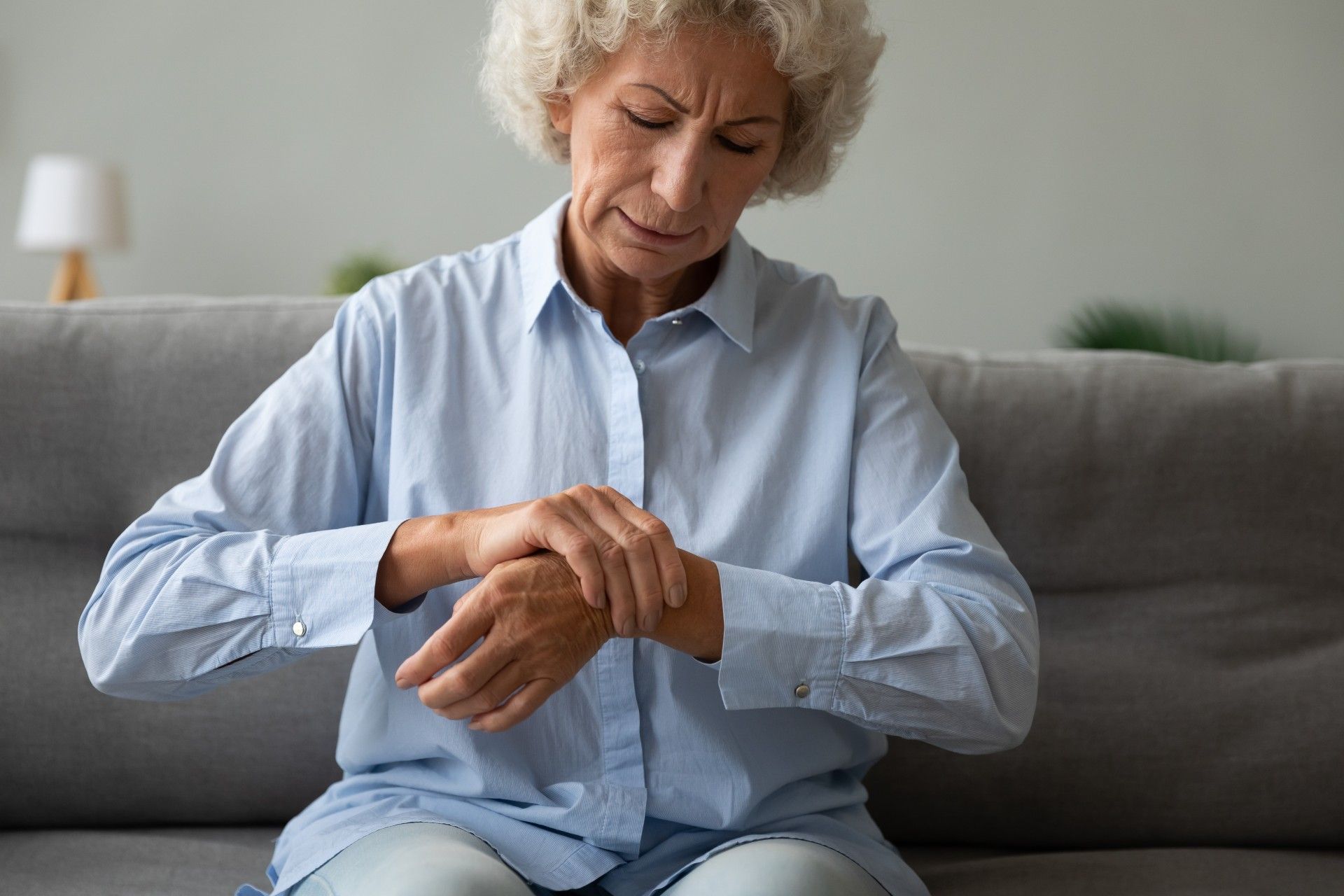 An upset older woman grabs her left wrist with her right hand - walmart glucosamine joint supplements
