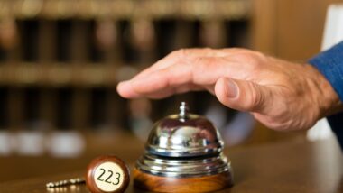 man's hand ringing bell at hotel reception desk
