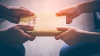 two people holding holy bible, hands close up
