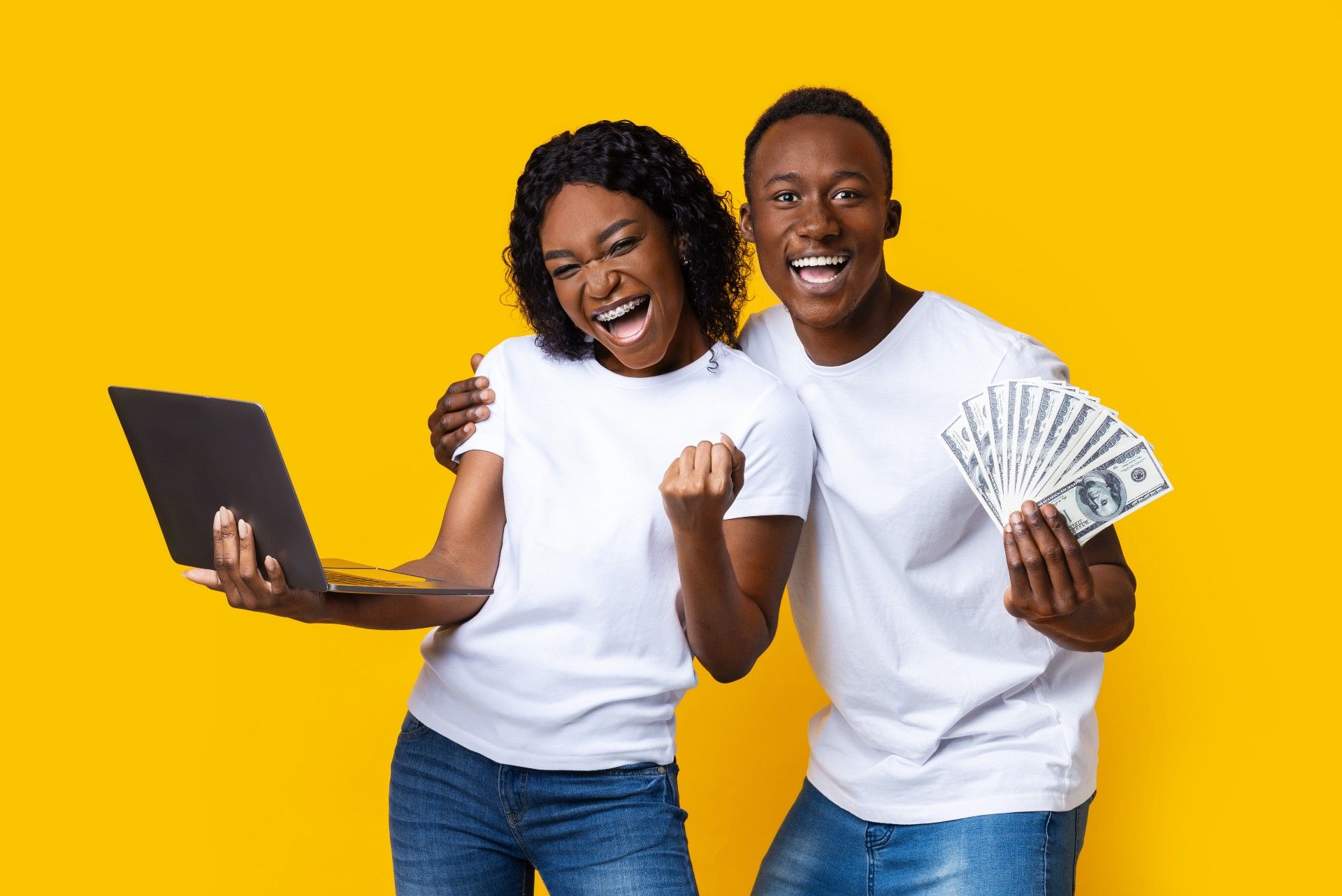 Against a yellow background, a happy woman holds a laptop, while a happy man holds up fanned-out cash - settlement payouts
