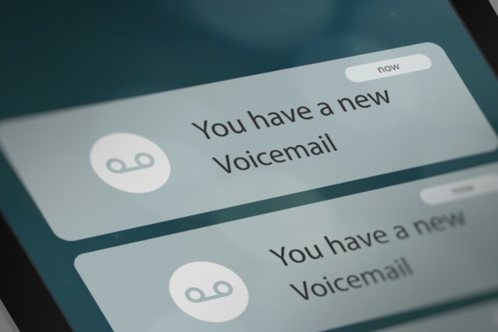 A smartphone screen shows notifications of two new voicemails - Penn Credit - pre-recorded voicemail