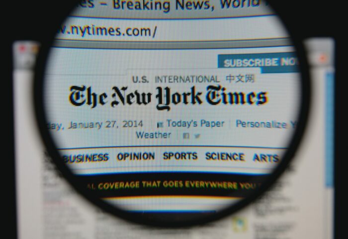 The New York Times homepage is seen under a magnifying glass - new york times subscription