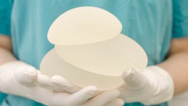 gloved surgeon hands holding breast implants