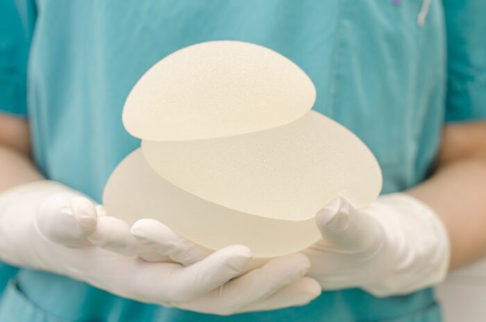 gloved surgeon hands holding breast implants