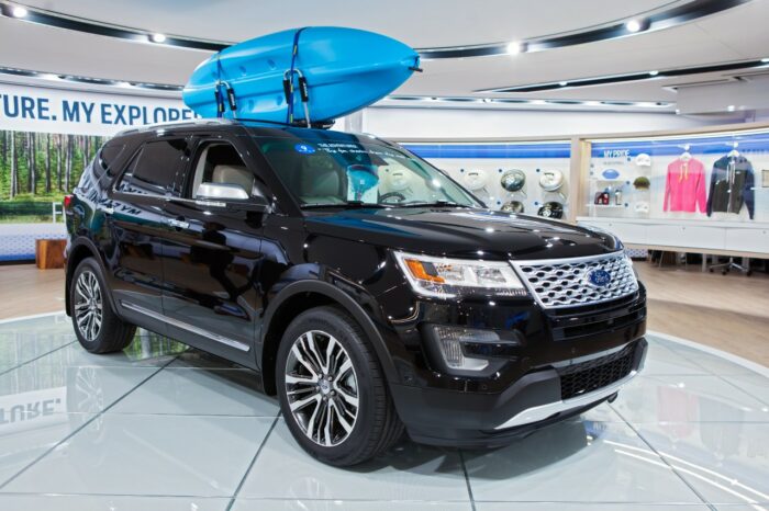 A black Ford Exlorer with a blue kayak strapped to the top sits in a showroom - Ford Explorer exhaust - ford class action - explorer exhaust settlement claim form