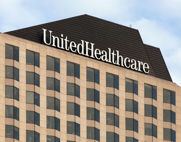 A "UnitedHealthcare" sign is seen on the roof of a building, representing the liposuction claims class action lawsuit.