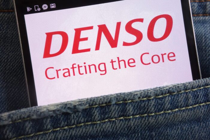 DENSO logo on the screen of a smartphone sticking out of a denim pocket - heater control panels - denso price fixing - auto parts lawsuit