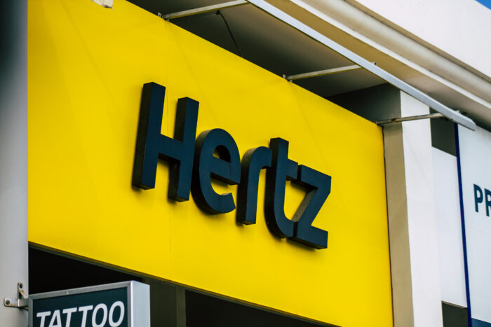 View of a commercial Hertz sign on the street. Hertz is facing a class action for clients being charged with stolen cars