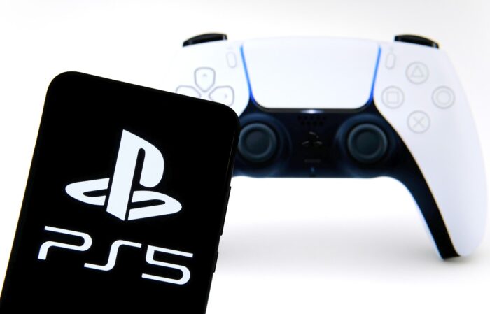 Sony PS5 logo seen on smartphone and official PS5 DualSense controller