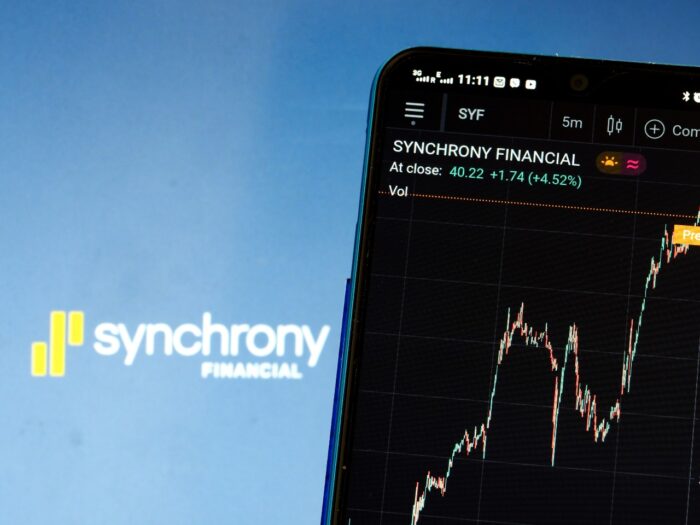 In this photo illustration the stock market information of Synchrony Financial displays on a smartphone while the logo of Synchrony Financial displays as background - ge capital bankruptcy - synchrony bank settlement