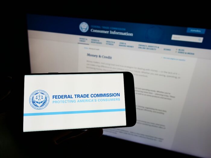 Person holding cellphone with logo of US government agency Federal Trade Commission (FTC)