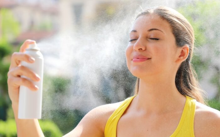 Young woman spraying Thermal Water