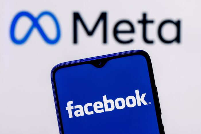 Smartphone with Facebook logo on the background of Meta logo.