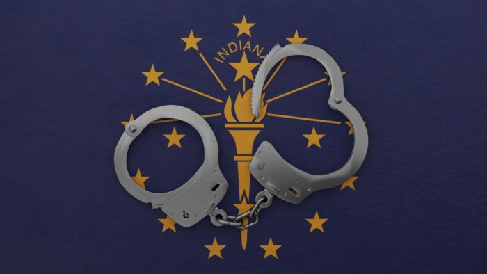 rendering of a half opened steel handcuff in center on top of the US state flag of Indiana - jail settlement