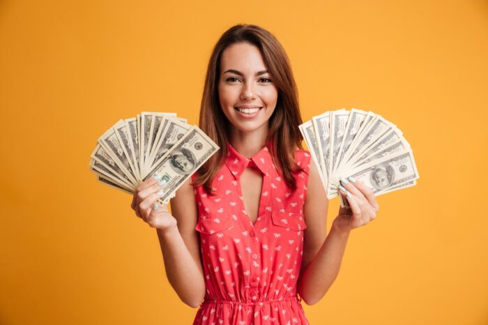 Young cheerful woman holding two fans of money.