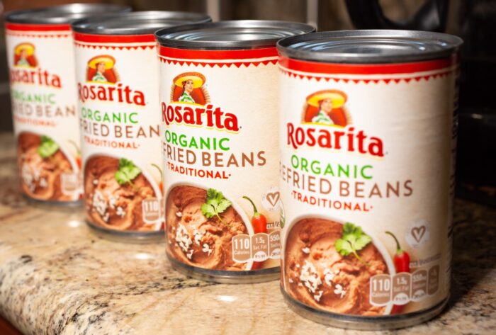 A row of four cans of Rosarita Organic Refried Beans