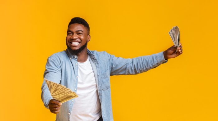 Man Holding A Lot Of Money In Both Hands On Yellow Background